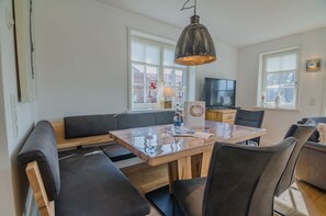 A modern dining area with a wooden table, black cushioned benches, and a hanging pendant light.