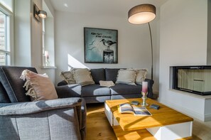 A modern living room with a grey sofa, a wooden coffee table, and a large window.