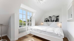 Une chambre à coucher avec un lit, une fenêtre, un tableau et une lampe de sol.