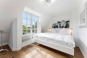 Une chambre à coucher avec un lit, une fenêtre, un tableau et une lampe de sol.
