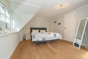 Un dormitorio con cama, mesita de noche y ventana con persianas.