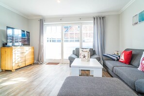 Una sala de estar moderna con un sofá gris, un mueble de madera y un televisor de pantalla plana.