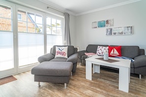 En moderne stue med grå sofaer, et hvidt sofabord og et stort vindue med gardiner.