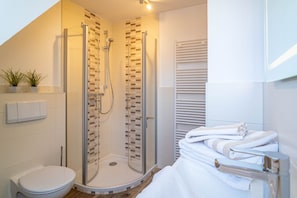 A modern bathroom with a glass-enclosed shower, a toilet, and a towel rack with folded towels. - Haus Strandoase - NEU NEU Neu!!! Ab Januar 2023 bei uns in der Vermittlung. - Mit Süd Terrasse und (Sylt)