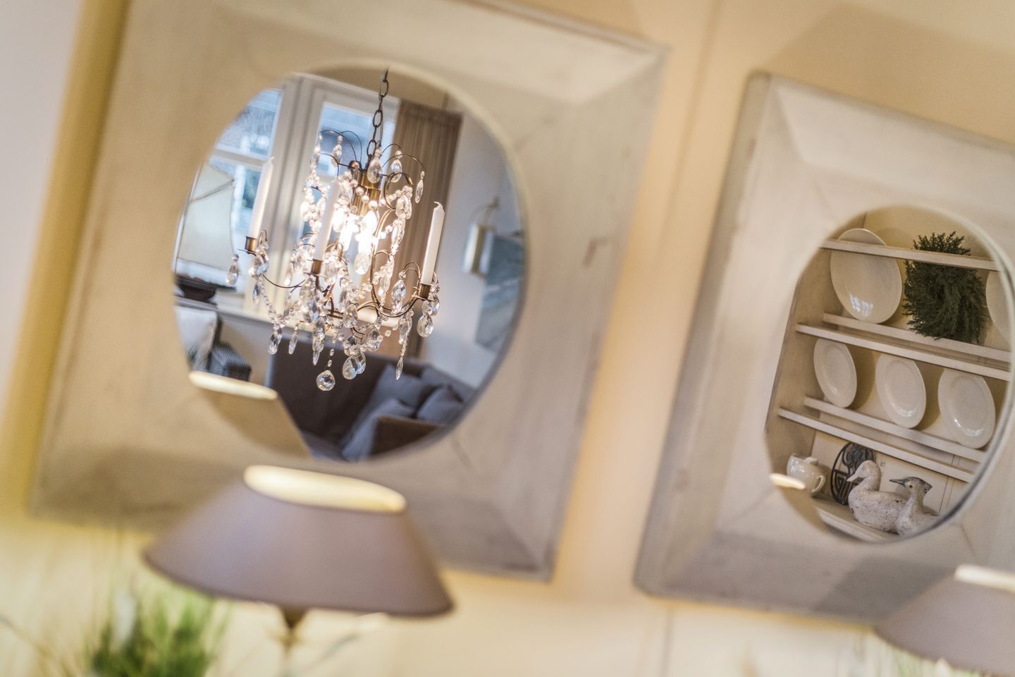 Une pièce dotée d’un lustre, d’un miroir et d’une étagère où sont disposés des objets décoratifs.
