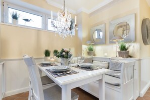 Un comedor con una mesa blanca dispuesta para cuatro personas, rodeado de bancos a cuadros.