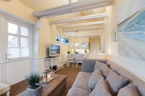 Un salon confortable avec un canapé, un téléviseur et un coin repas comprenant des chaises et une table.