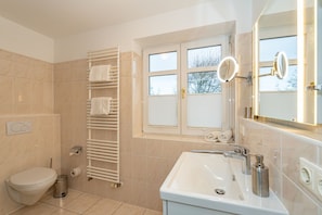 A modern bathroom with a toilet, sink, and towel rack. - Wildente App. 5 - Zentral Gelegene 2-zimmerwohnung in Wenningstedt am Dorfteich (Wenningstedt-Braderup (Sylt))