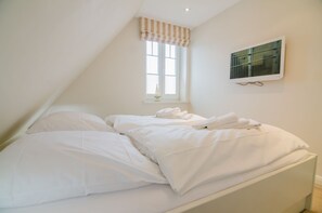 Une chambre à coucher avec un lit, une fenêtre avec des stores et un climatiseur fixé au mur.