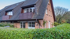 Et toetagers hus med skråt tag, murstensfacade og store vinduer.