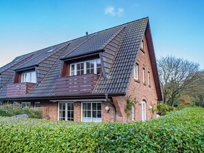 A two-story house with a sloped roof, brick exterior, and large windows. - Kate Kleinod - Neu!!! Ab September 2022 in der Vermittlung. - Schönes Reihenendhaus in Ruhiger Lage (Sylt-Ost)