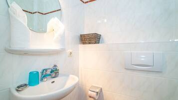 A bathroom with a white sink, a mirror, a towel rack, a toilet paper holder, and a soap dispenser.