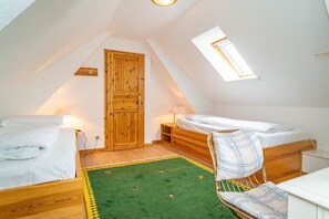 A small, cozy attic bedroom with two beds, a green rug, and a skylight. - Kate Kleinod - Neu!!! Ab September 2022 in der Vermittlung. - Schönes Reihenendhaus in Ruhiger Lage (Sylt-Ost)