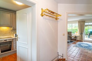A kitchen with white cabinets, a stainless steel oven, and a gold decorative rack on the wall.