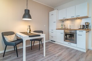A modern kitchen with white cabinets, a built-in oven, and a coffee machine.