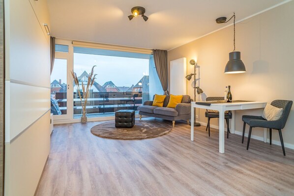 A modern living room with a sofa, ottoman, and dining area.
