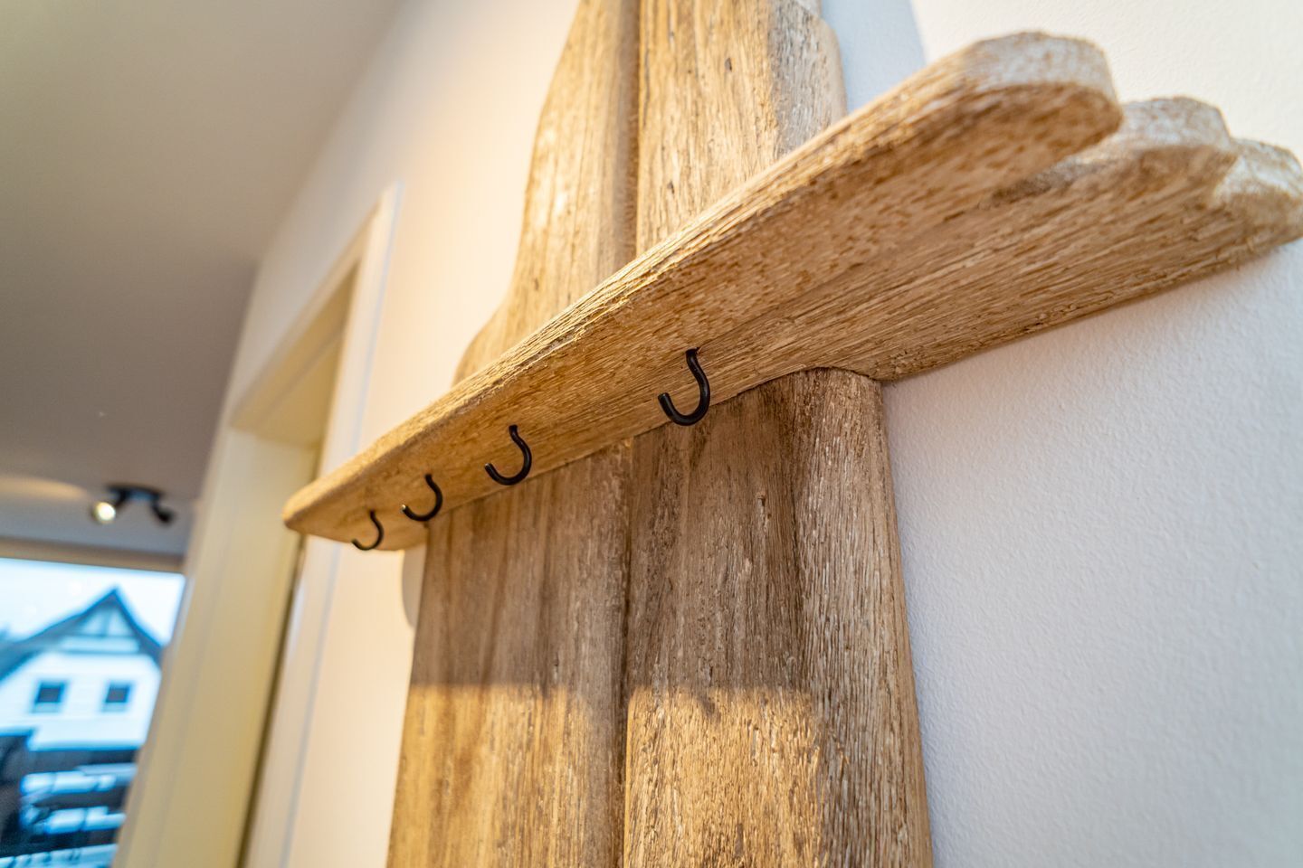 Un porte-manteau en bois muni de crochets portant les lettres « U », « J » et « J ».