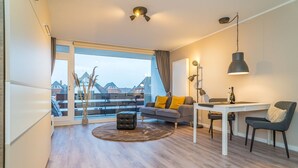 Ein modernes Wohnzimmer mit einer Couch, einem Hocker und einem Essbereich.