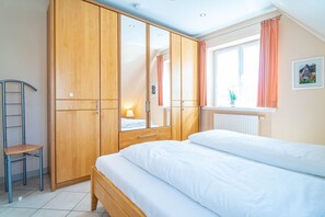Quarto com cama, guarda-roupa de madeira e janela com cortinas.