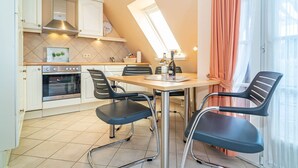 Une cuisine moderne avec un coin repas, comprenant un four encastré, une table à manger avec des chaises et une grande fenêtre avec des rideaux.