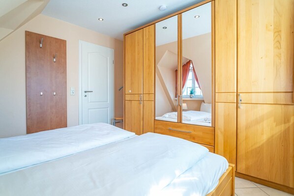 A bedroom with a bed, wooden wardrobe, and a white door.