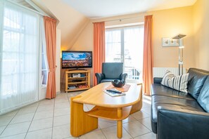Un salon avec un canapé, une table basse, un téléviseur et une bibliothèque.