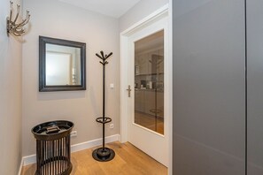 A hallway with a mirror, a coat rack, and a door leading to a kitchen.