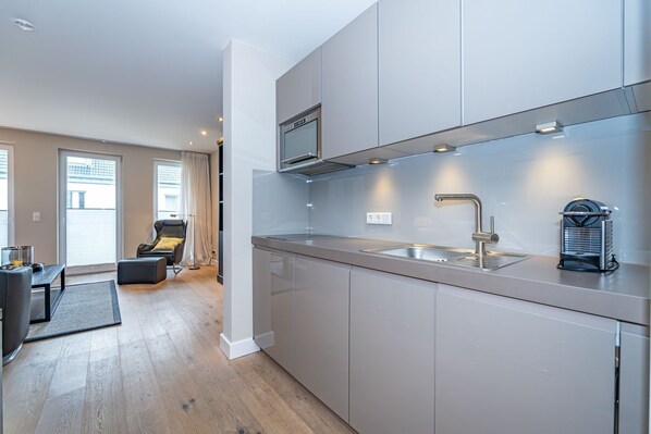 A modern kitchen with a stainless steel sink, a microwave, and a coffee machine.