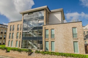 Un bâtiment moderne doté d’une façade en verre, d’une structure extérieure en briques et de nombreuses fenêtres.