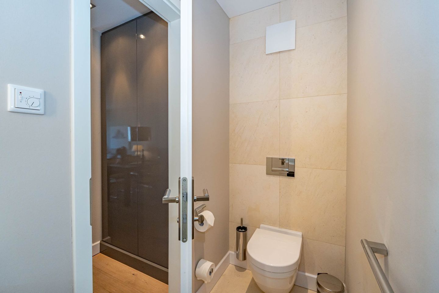 Ein modernes Badezimmer mit Toilette, Duschbereich und einer Glastür zu einem Flur.