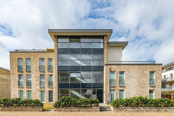 A modern building with a large glass facade, multiple windows, and a brick exterior.