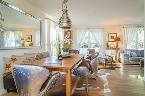 Un espace repas avec une table en bois, des chaises en cuir et un luminaire suspendu.