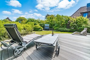 A deck with two lounge chairs and a bottle of wine, surrounded by lush greenery and a clear blue sky. - Maarwiet Hüs - Holiday home (detached house) for up to 6 persons with garden and (Wenningstedt-Braderup (Sylt))