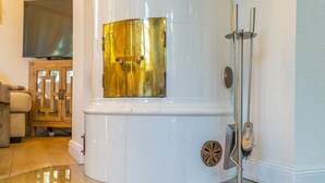 A modern, compact sauna with a gold-tubed section, a steam shower, and a metal stand.
