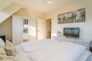 Ein Schlafzimmer mit zwei Betten, einem Fernseher, einem Gemälde und einem Kleiderschrank.