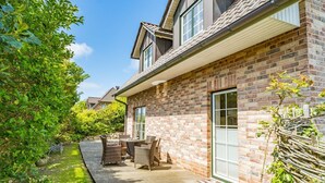 A brick house with a patio, outdoor furniture, and a garden.