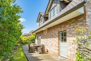 Une maison en briques avec un patio, du mobilier d’extérieur et un jardin.