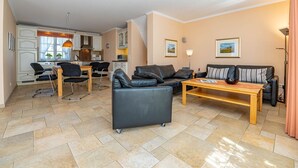 Un salon moderne comprenant un canapé, une table basse et un coin repas avec des chaises et une table.