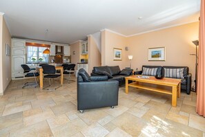 Ein modernes Wohnzimmer mit Sofa, Couchtisch und Essbereich mit Stühlen und einem Tisch.