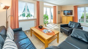 Un salon moderne avec un canapé, une table basse et un téléviseur.