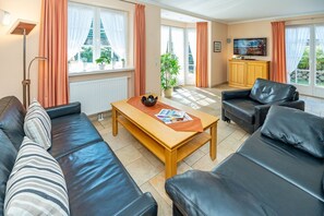 Ein modernes Wohnzimmer mit einer Couch, einem Couchtisch und einem Fernseher.