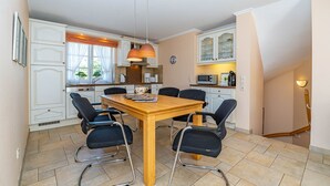Un coin repas avec une table en bois, six chaises et un luminaire suspendu.