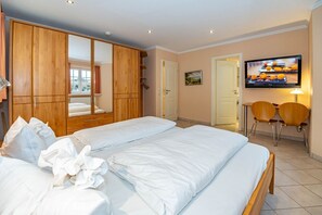 Habitación de hotel con una cama grande, armario de madera, televisor y dos sillas.