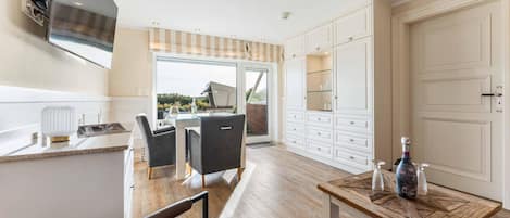 A modern kitchen with a dining area, a large window, and a view of the outdoors.