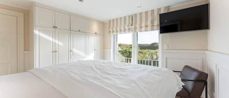 Une chambre à coucher avec un grand lit, une armoire et un téléviseur fixé au mur.
