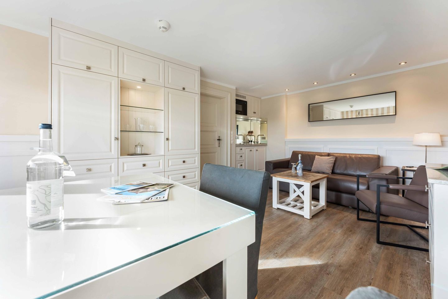 A modern living room with a glass-top dining table, a sofa, and a coffee table.