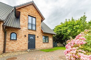 A two-story brick house with a black door, two windows, and a tiled roof. - Gode Stuv - Holiday home for up to 6 people with garden and sauna. (Sylt)