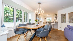 A modern kitchen with a wooden table, grey chairs, and a pendant light. - Gode Stuv - Holiday home for up to 6 people with garden and sauna. (Sylt)