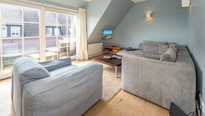 Una sala moderna con dos sofás grises, una mesa de centro de madera y un televisor sobre un mueble bajo.