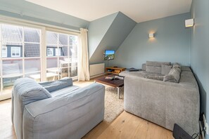 Una sala moderna con dos sofás grises, una mesa de centro de madera y un televisor sobre un mueble bajo.